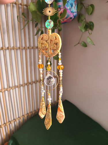 Maori suncatcher with gold elements and beads against a neutral background