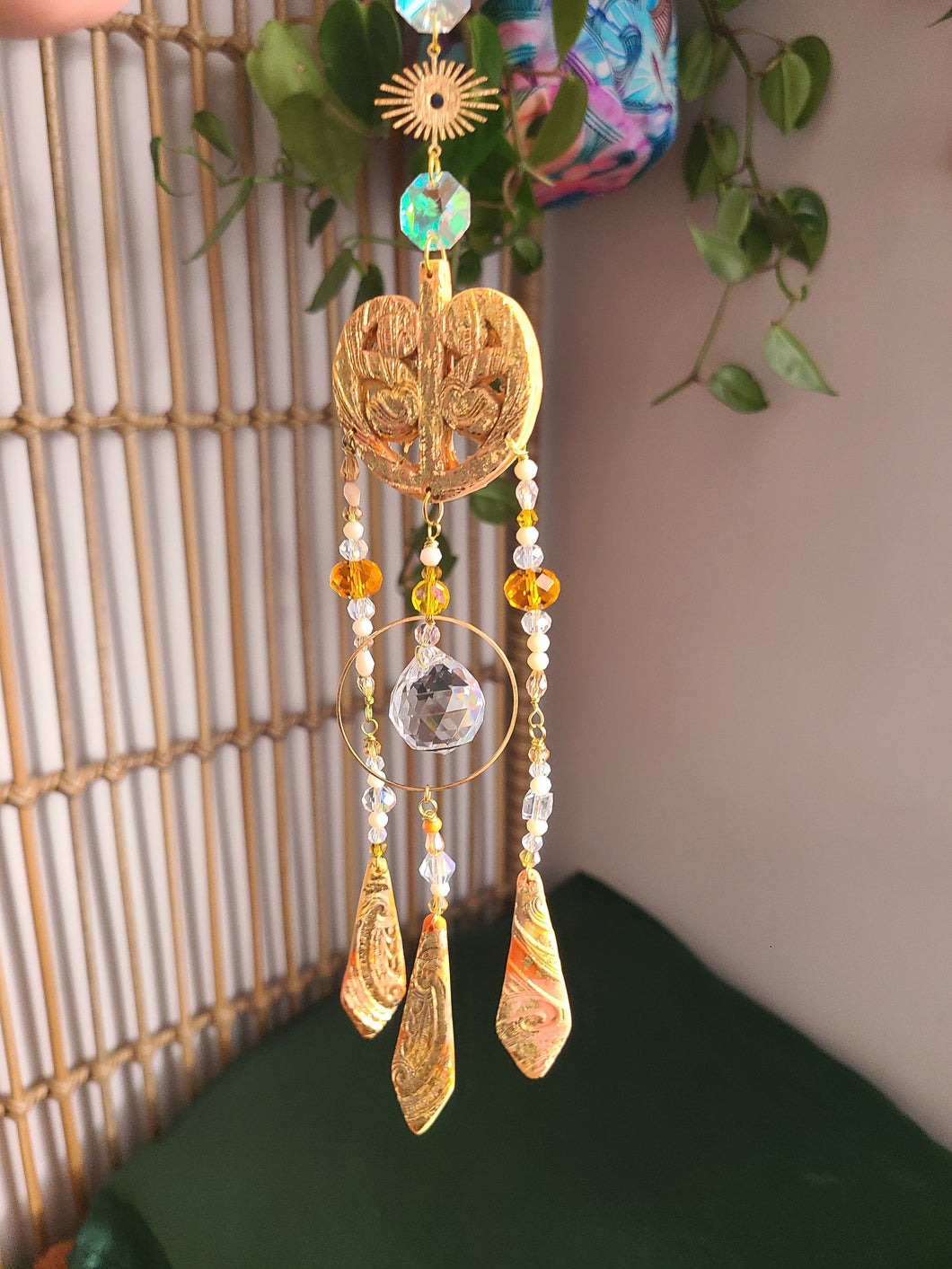 Maori suncatcher with gold elements and beads against a neutral background